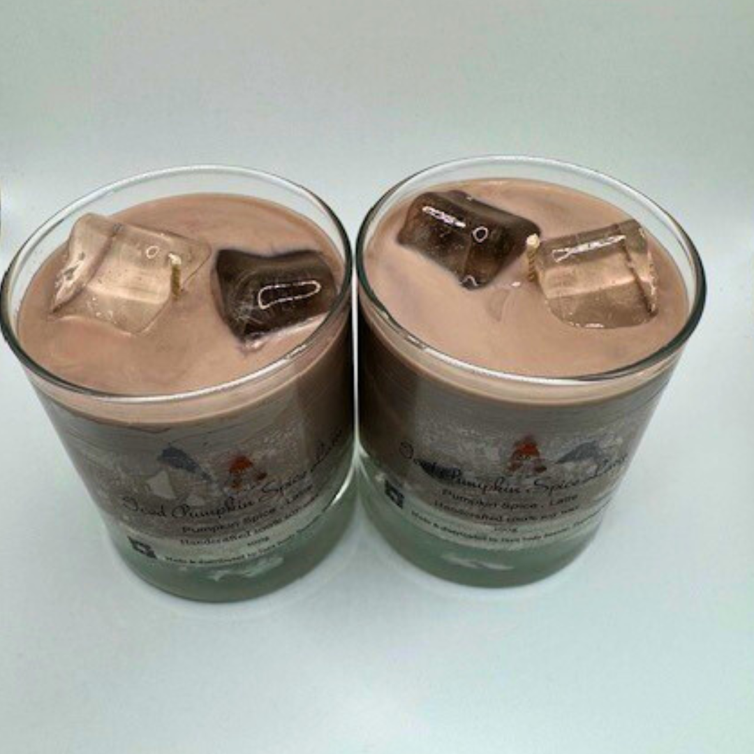 A single-wick candle in a clear jar, designed to resemble an iced latte, with a white layer at the bottom, a rich brown coffee-colored wax, and a clear ice cube detail on top.