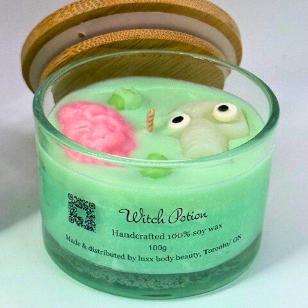 A light green, single-wick candle in a clear jar with a bamboo lid, featuring a skull, pink brain, and bubbles decoration on top—perfect for Halloween.