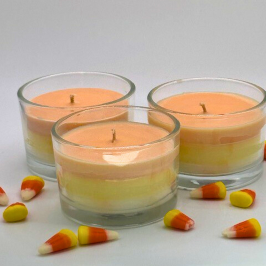 A single wick candle in a clear jar. Made of white, yellow, and orange layers, same as candy corn.