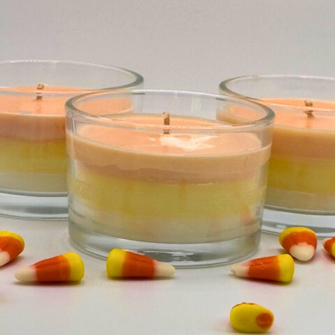 A single wick candle in a clear jar. Made of white, yellow, and orange layers, same as candy corn.