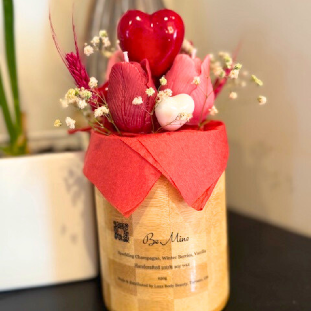 A wooden vase filled with candles shaped like pink and red roses. decorated with big red heart in the middle and botanical flora with many other small hearts