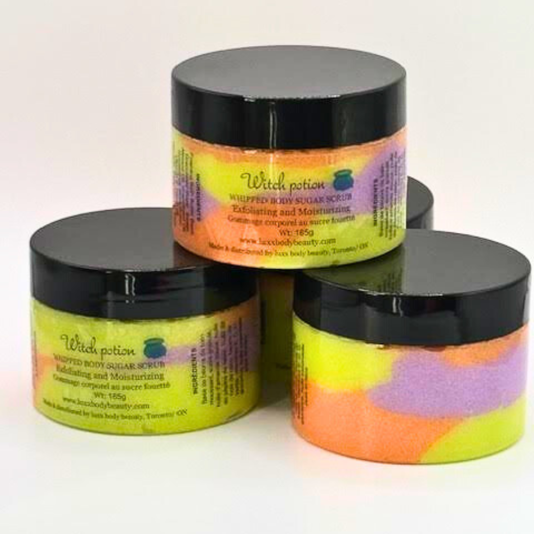A whipped sugar scrub in a clear jar with layered light green, orange, purple, and yellow colors.