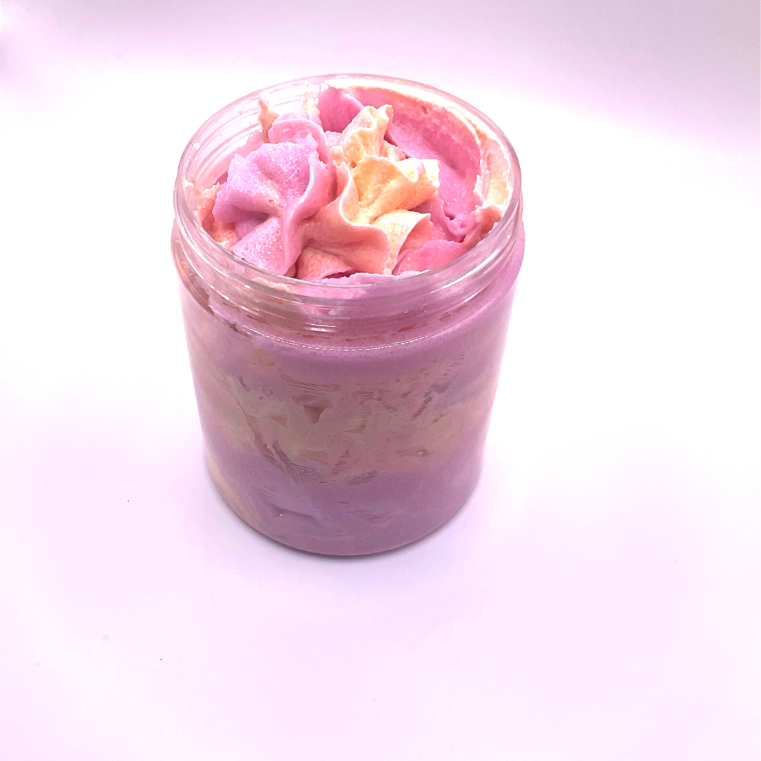 A whipped foamy sugar scrub in purple and yellow colors, piped into a clear jar.