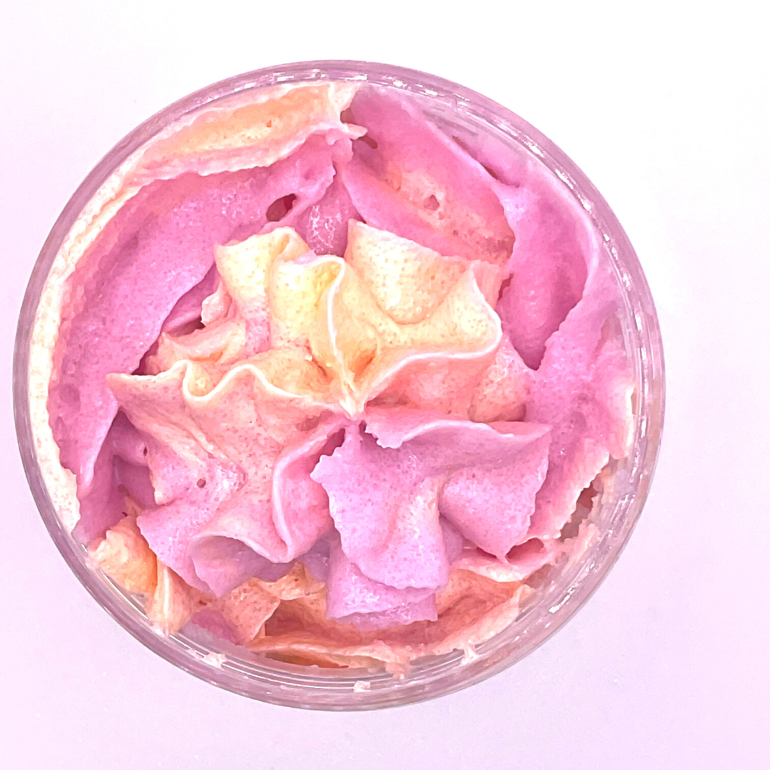 A whipped foamy sugar scrub in purple and yellow colors, piped into a clear jar.