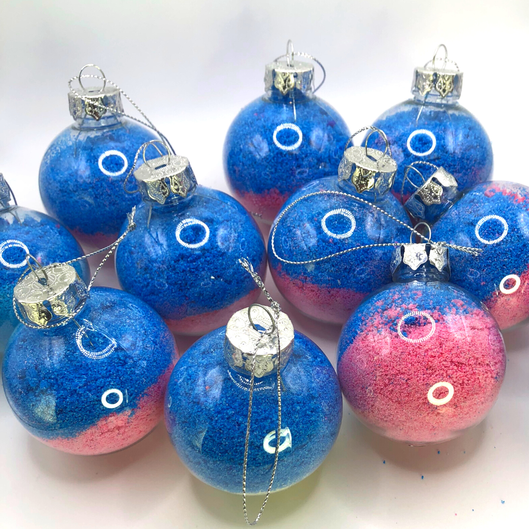 A bath crumble in pink, blue, and purple colors is placed inside a Christmas tree ornament.