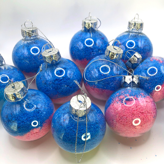 A bath crumble in pink, blue, and purple colors is placed inside a Christmas tree ornament.