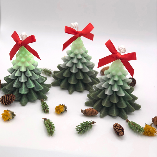A Christmas tree-shaped candle with snow on top, decorated with a red bow.