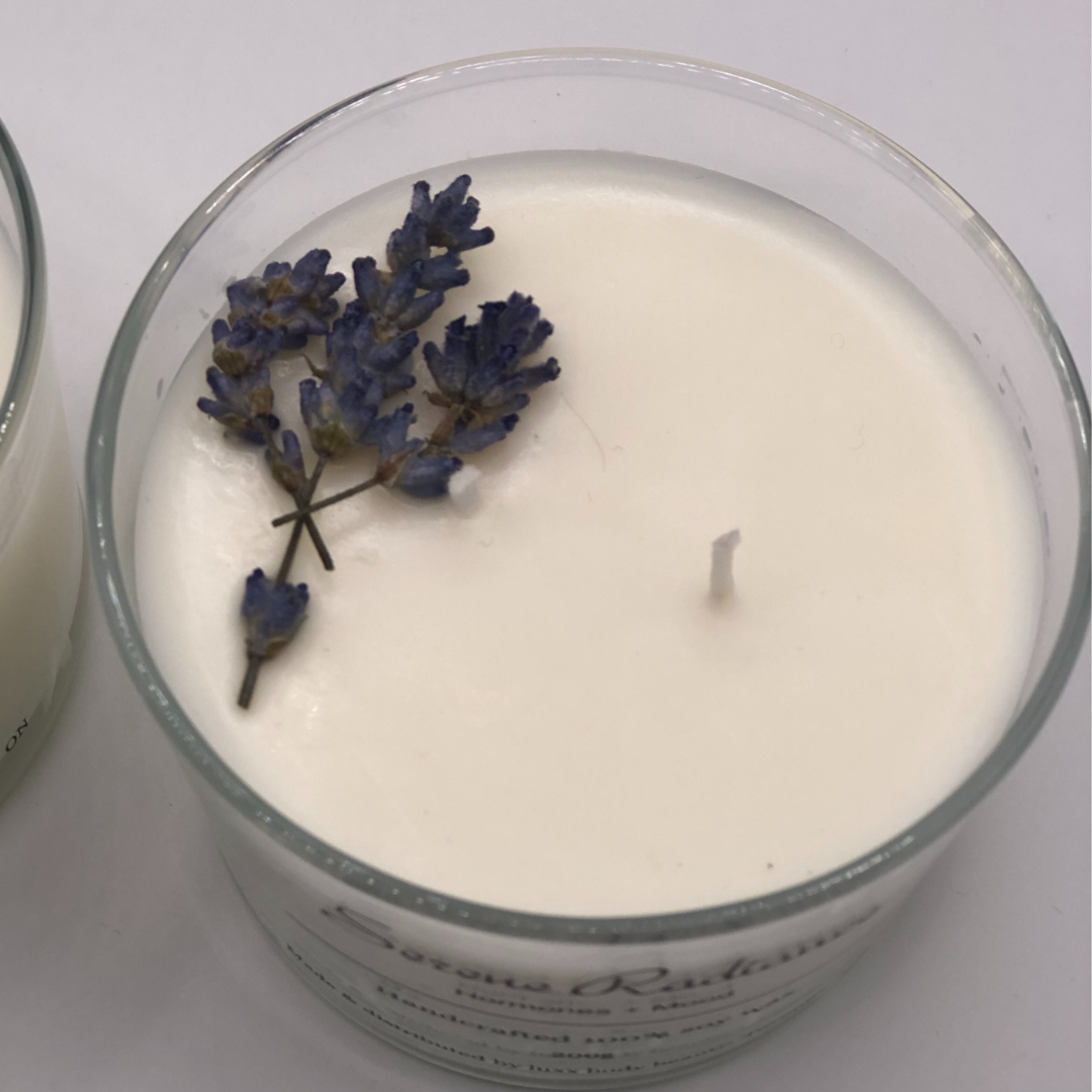 A single-wick white candle in a clear jar, topped with a dried Lavender floral decoration.