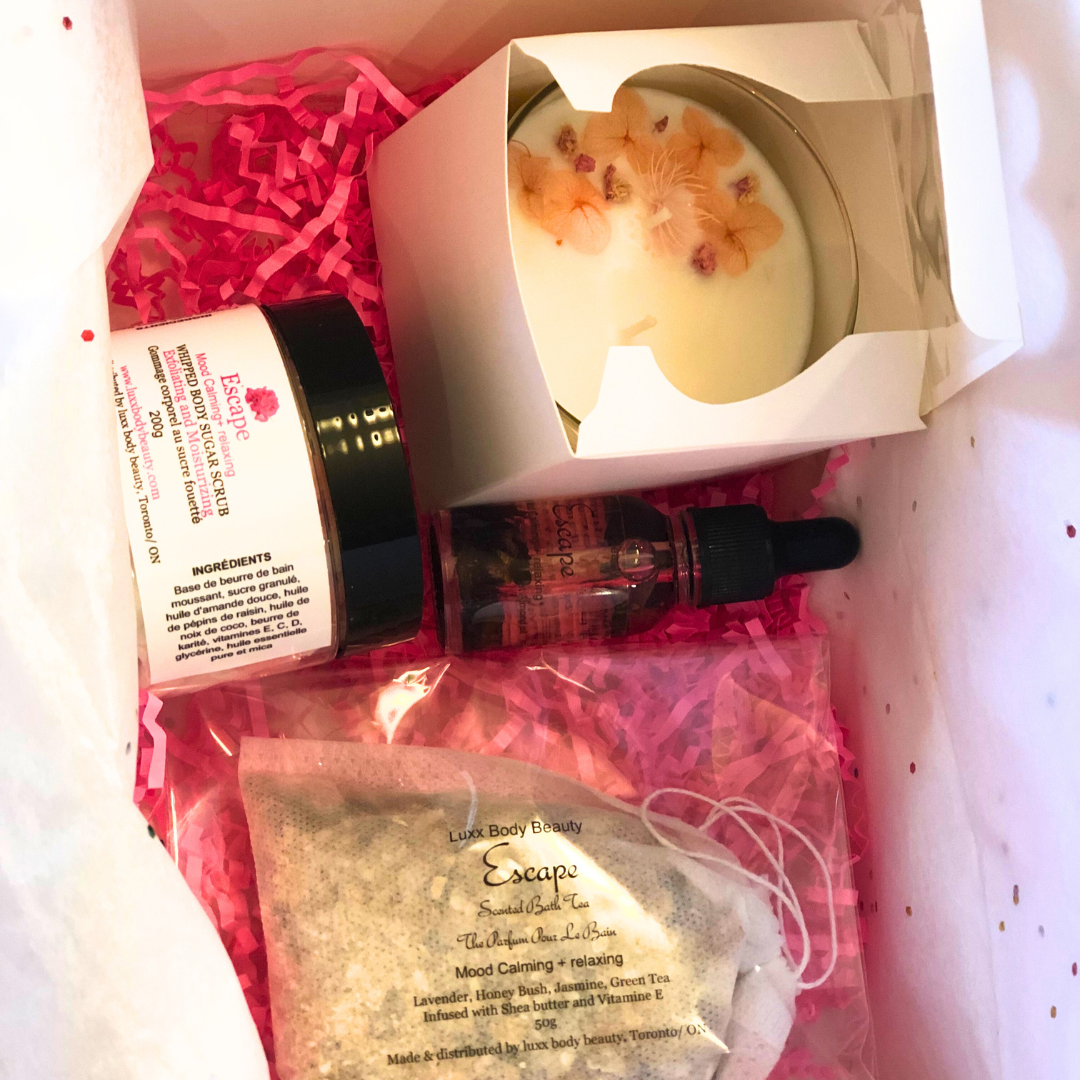 A home spa day set featuring a candle, body oil bottle, bath tea, and sugar scrub jar.