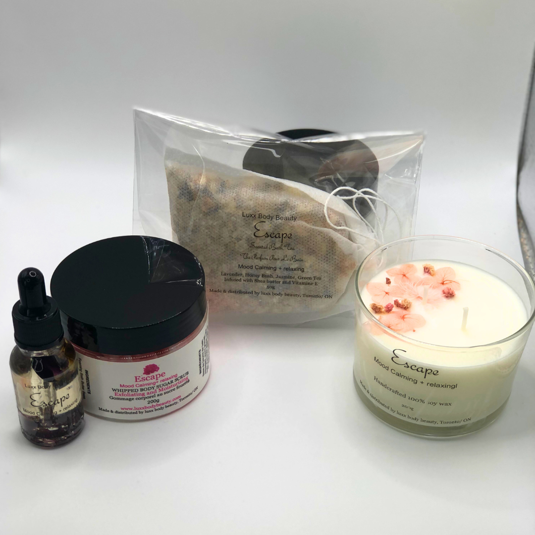 A home spa day set featuring a candle, body oil bottle, bath tea, and sugar scrub jar.