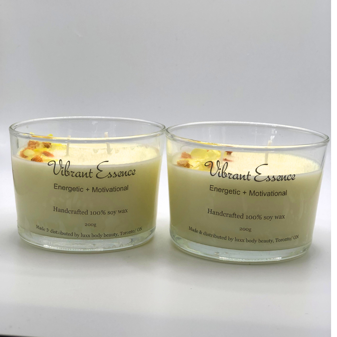 A single-wick white candle in a clear jar, topped with a dried yellow and orange floral decoration.