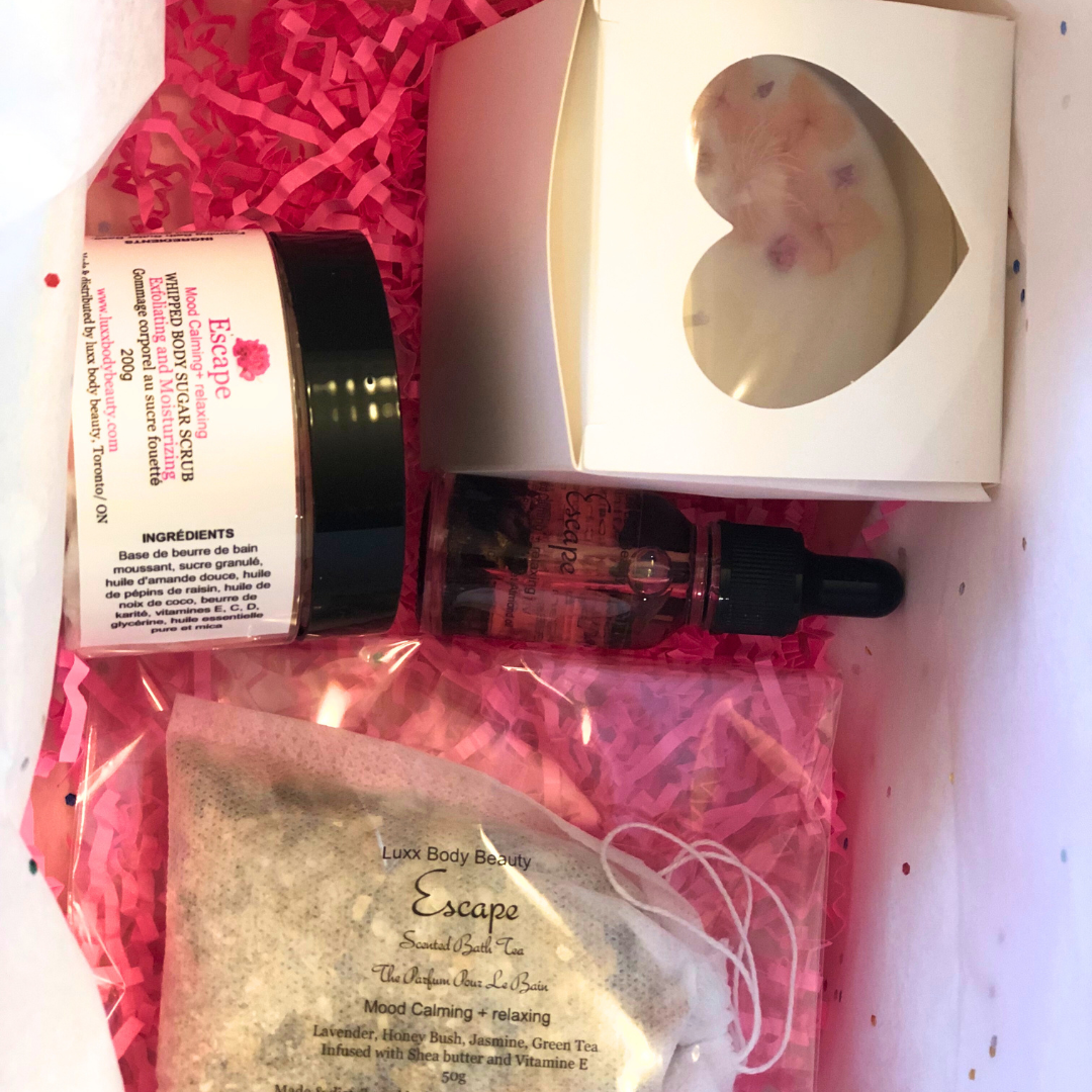 A home spa day set featuring a candle, body oil bottle, bath tea, and sugar scrub jar.