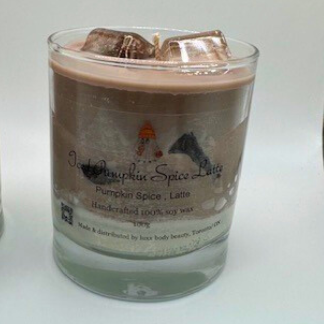 A single-wick candle in a clear jar, designed to resemble an iced latte, with a white layer at the bottom, a rich brown coffee-colored wax, and a clear ice cube detail on top.