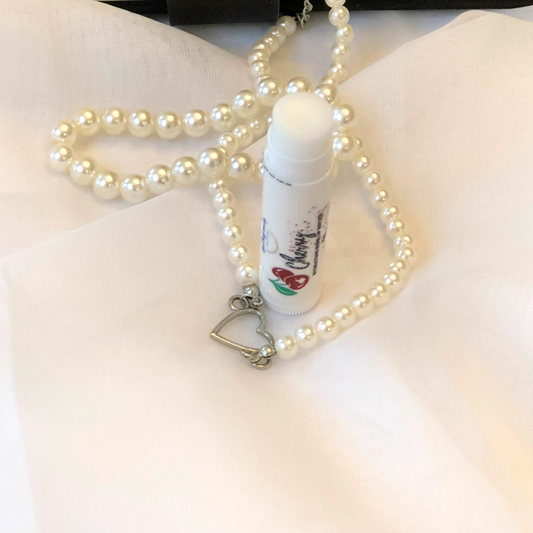 A white lip balm stick with a cherry image on the label, set against a white and pearl background.