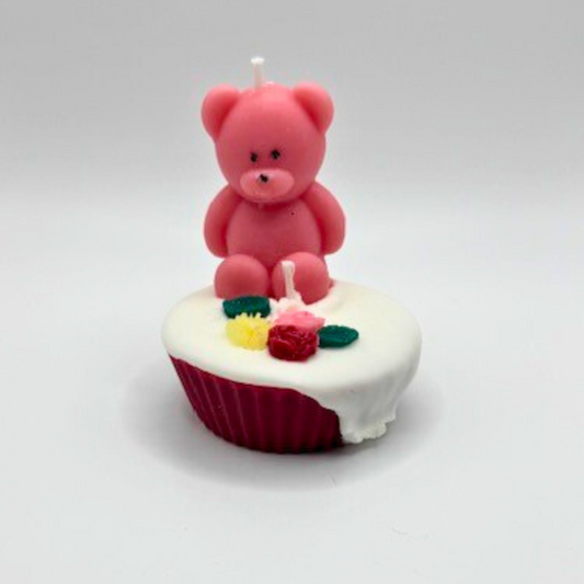 A double wicks cupcake candle in pink, decorated with a teddy bear and flowers on top.