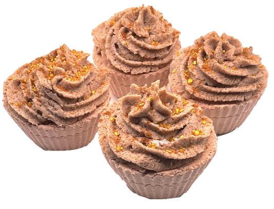 A light brown cupcake-shaped bath bomb topped with light brown bubble bath icing, topped with golden pearls.