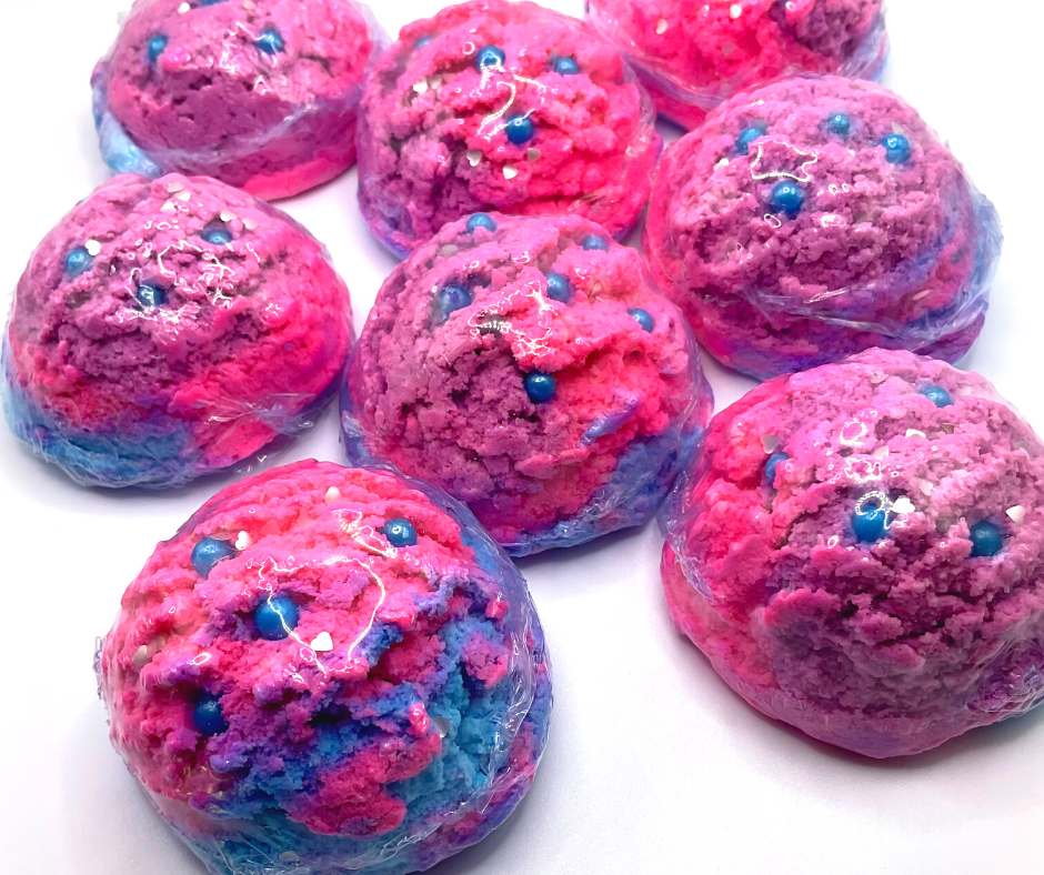 An ice cream scoop-shaped bubble bath in pink, purple, and blue, decorated with blue pearls.