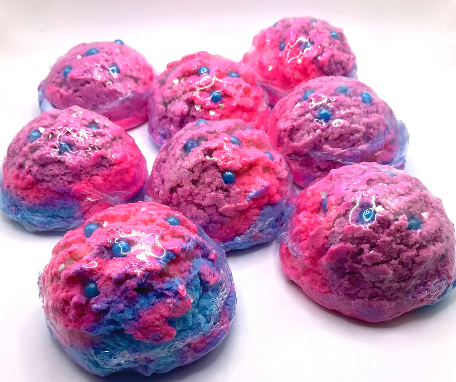 An ice cream scoop-shaped bubble bath in pink, purple, and blue, decorated with blue pearls.