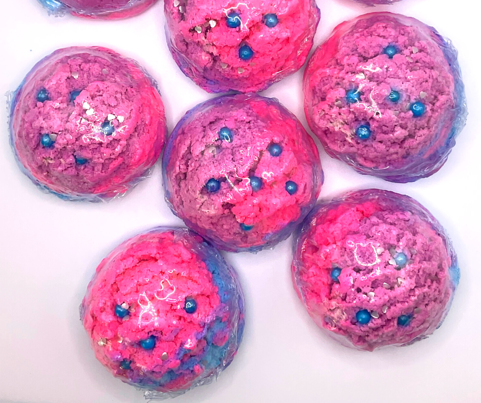 An ice cream scoop-shaped bubble bath in pink, purple, and blue, decorated with blue pearls.