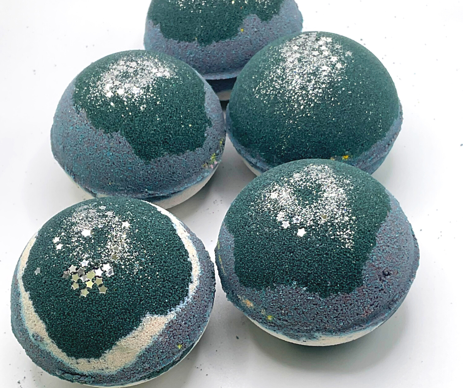 A round bath bomb with black, grey, and white colors, topped with silver stars.
