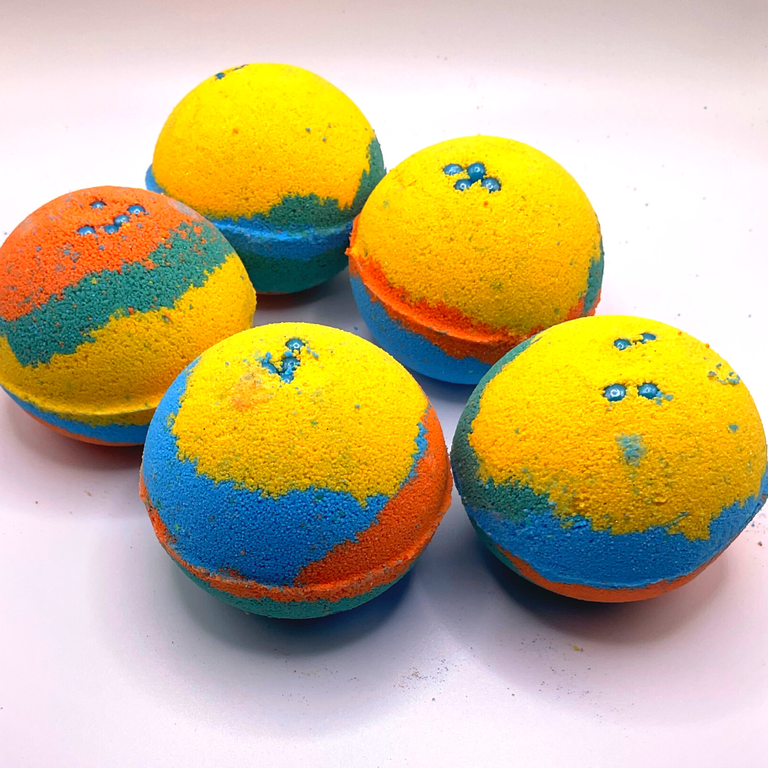 A round bath bomb with yellow, green, blue, and orange colors, topped with blue pearls.