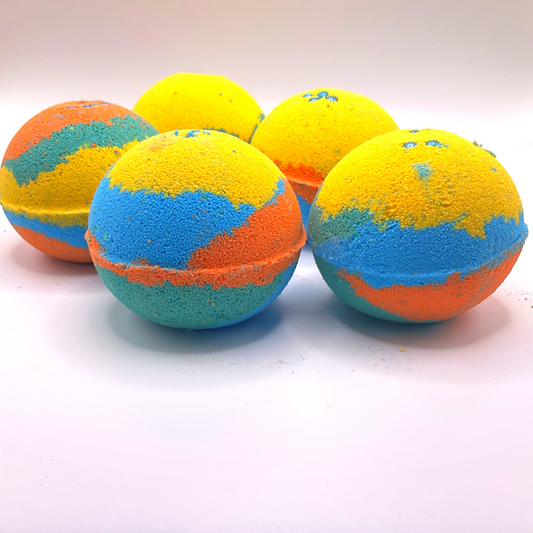 A round bath bomb with yellow, green, blue, and orange colors, topped with blue pearls.