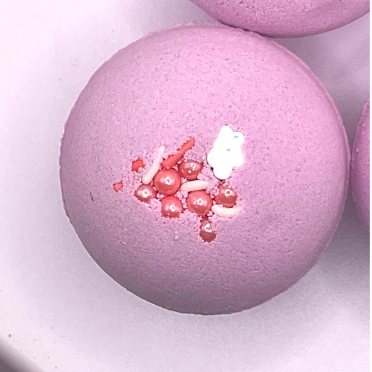 A purple round bath bomb topped with white and pink pearls.