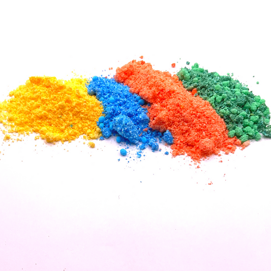 A yellow, blue, orange, and green bath bomb crumble in a striped pattern.