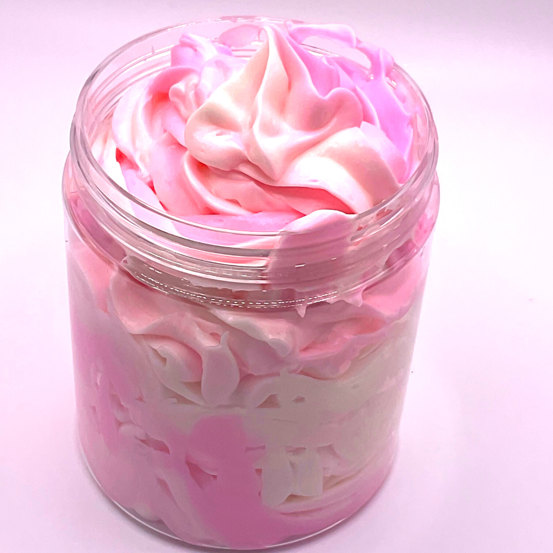 A whipped foamy sugar scrub of pink and white colors piped in a clear jar.