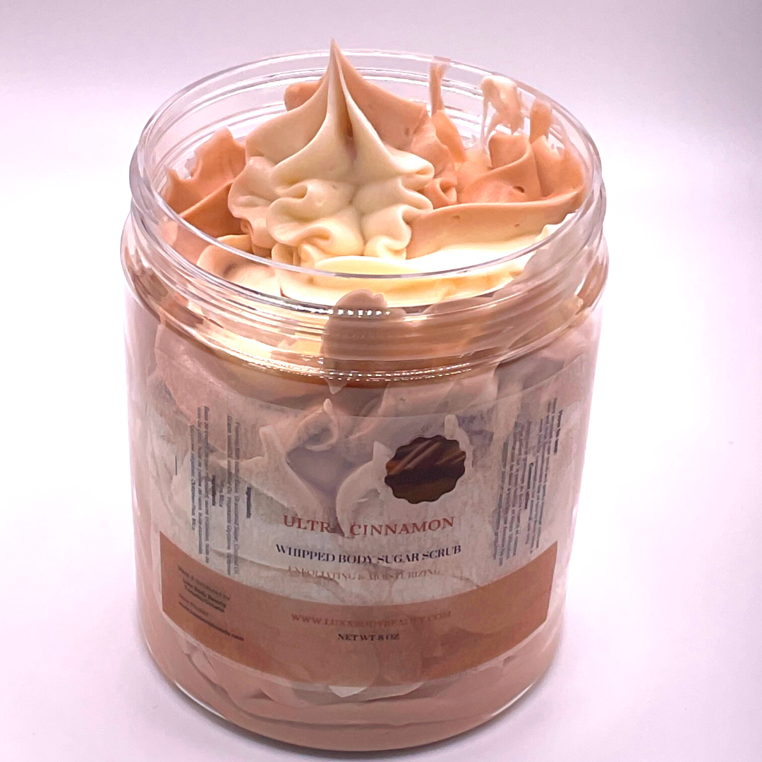 A whipped foamy sugar scrub of light brown and off-white colors piped in a clear jar.