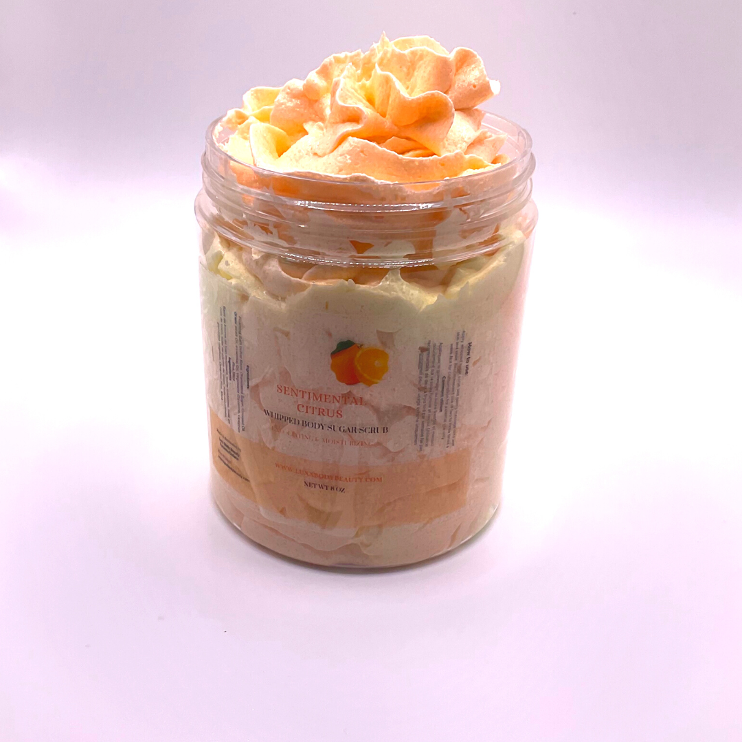A whipped foamy sugar scrub of yellow and orange colors piped in a clear jar.