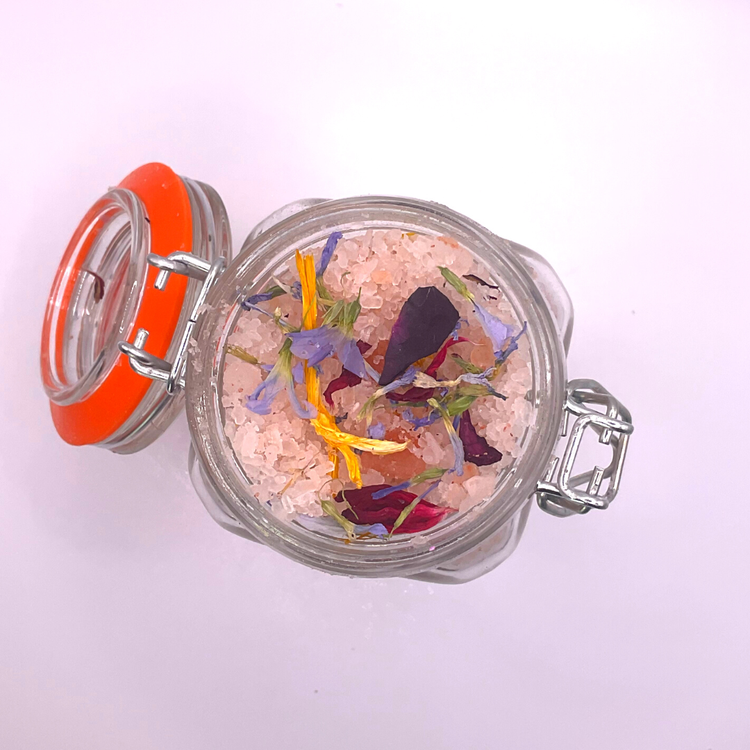 The top view of a clear jar filled with pink Himalayan salts mixed with dried florals.