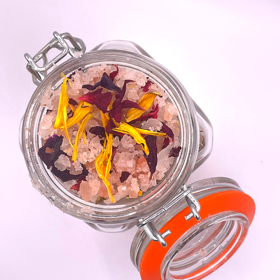 The top view of a clear jar filled with pink Himalayan salts mixed with dried florals.