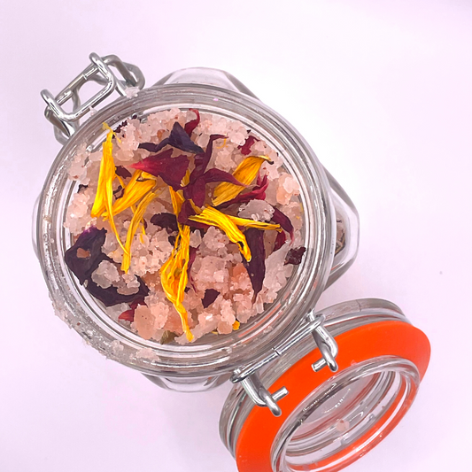 The top view of a clear jar filled with pink Himalayan salts mixed with dried florals.