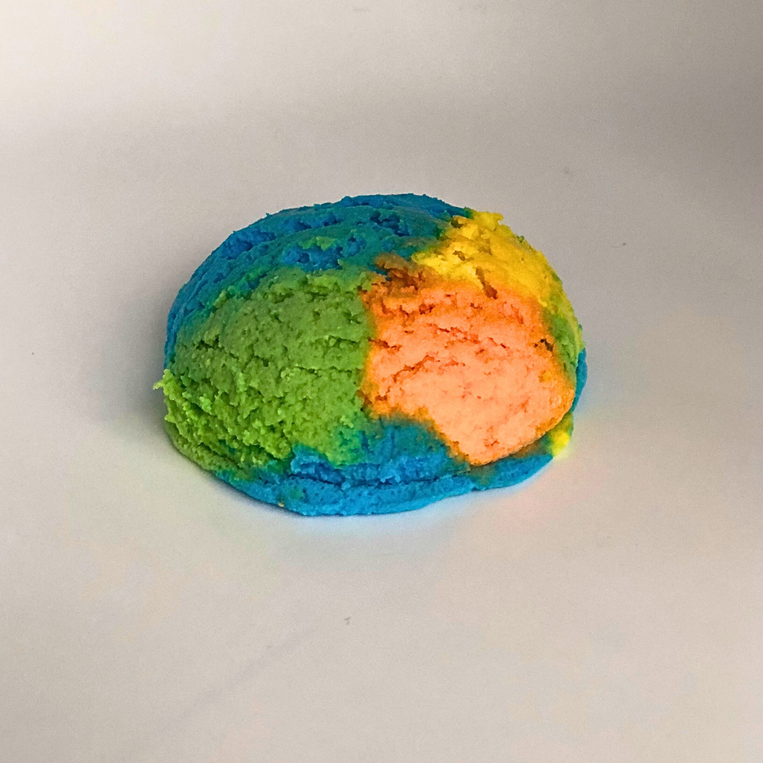 An ice cream scoop-shaped bubble bath in yellow, orange, green, and blue.