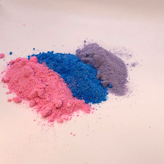 A pink, blue, and purple bath bomb crumble in a striped pattern.