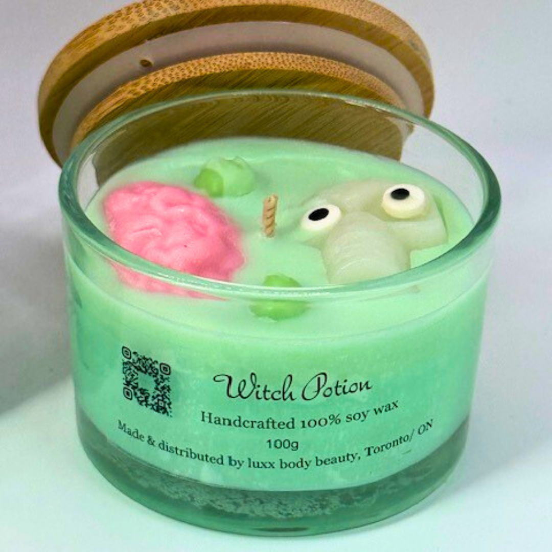 A light green, single-wick candle in a clear jar with a bamboo lid, featuring a skull, pink brain, and bubbles decoration on top—perfect for Halloween. 