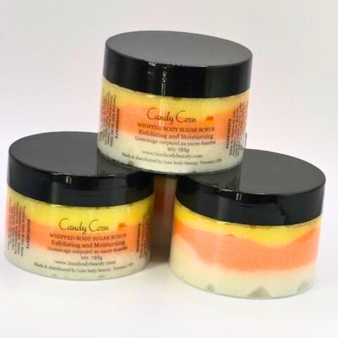 A whipped sugar scrub in a clear jar is made of white, orange, and yellow layers, the same as candy corn.