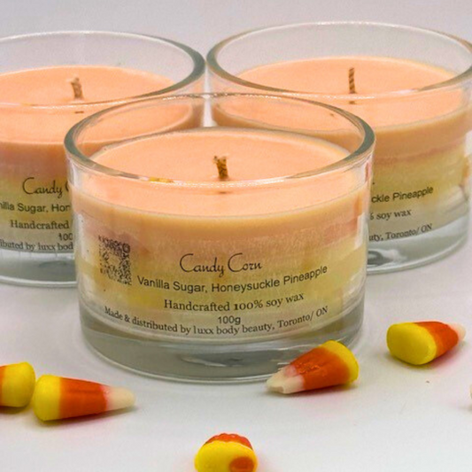 A single wick candle in a clear jar. Made of white, yellow, and orange layers, same as candy corn.