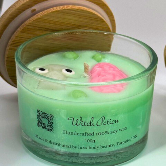 A light green, single-wick candle in a clear jar with a bamboo lid, featuring a skull, pink brain, and bubbles decoration on top—perfect for Halloween. 